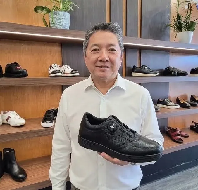 Geon Seo, shoe engineer at JGP USA on Oracle Road in Tucson, holding a black leather walking shoe